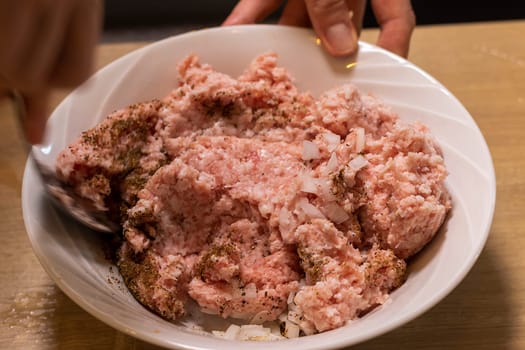 Just ground meat mince in the glass bawl of the electrical chopper on the kitchen counter top being seasoned and mixed. Cooking