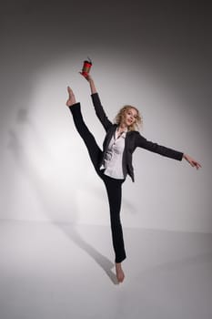 Barefoot ballerina in business suit dancing with a cup of coffee on a white background