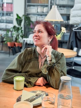 Woman smiling in cafe atmosphere with matcha. Joy, relaxation and mindful presence in everyday life.