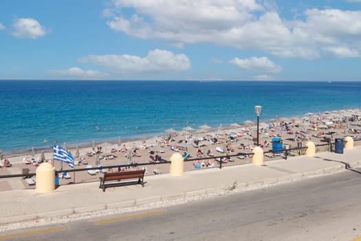 Rodas.Greece - june 07, 2025: Pebble beach in Rhodes, showing the interaction between bathers, beach facilities, and the vastness of the sea and sky, perfect for travel and leisure themes.