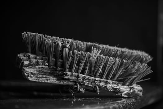 Monochrome close up image of an old, broken stable broom