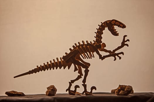 Wooden model of a Velociraptor silhouetted against a light background