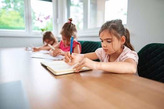 Young girls concentrate on their writing activities indoors