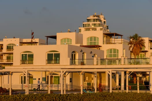 A serene view of a white villa complex in Cyprus bathed in warm sunset light,