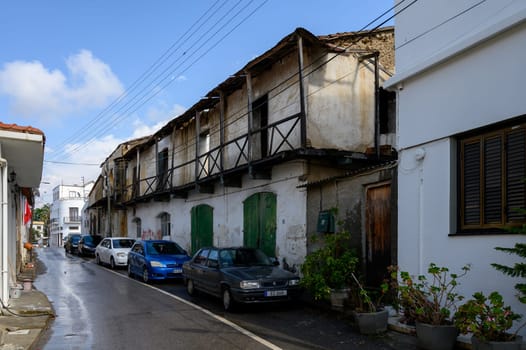 Narrow traditional street in Lefke, Cyprus with whitewashed houses, wooden doors and lush greenery.