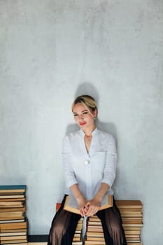 Business woman sitting on stacks of educational books in library
