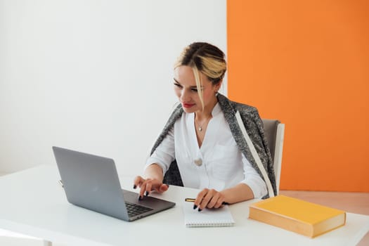 Business woman sitting at office desk and working on laptop online