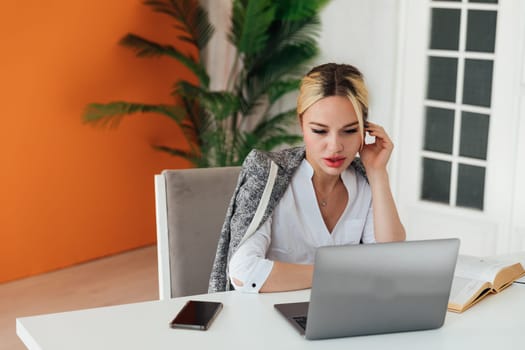 Business woman sitting at office desk and working on laptop online