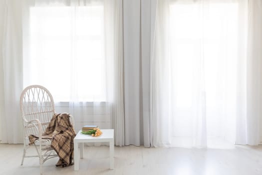 white old chair and table with book in the interior of a room with a window