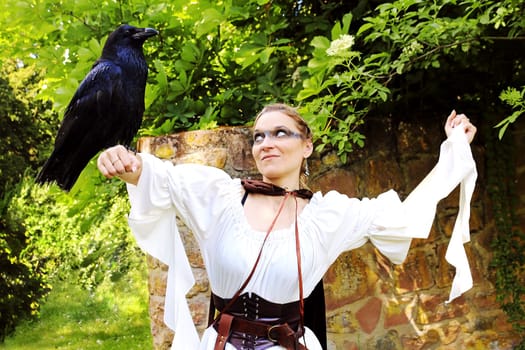 A woman dressed as a hunter with a raven on her arm