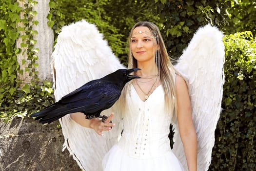 A woman dressed as an angel with a raven on her arm