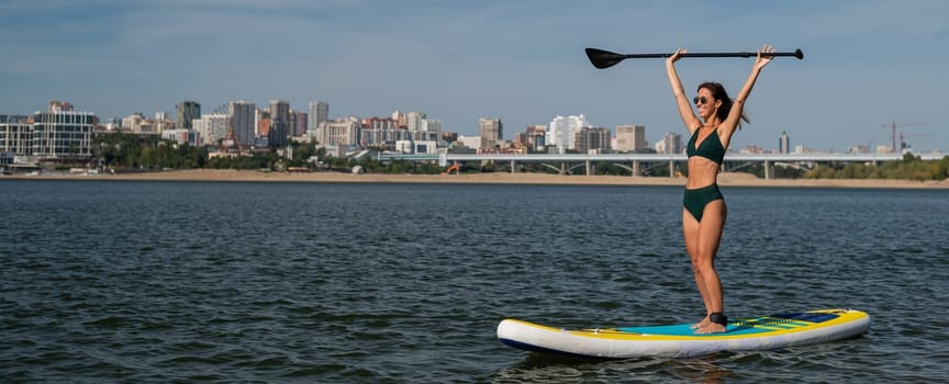 Caucasian woman riding a SUP board on the lake. Summer sport