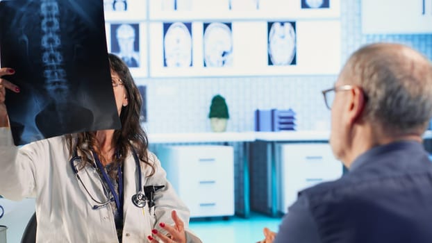 Old man receiving bad news of a dangerous disease diagnosis from his medic, discussing with physician about treatment. Worried distraught patient getting concerned of wellbeing. Camera B.