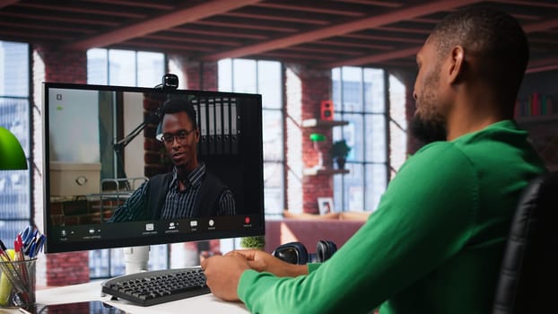 Male worker calls manager remotely using internet video call to ask for feedback on project progress. Teleworker requesting assistance from team leader in teleconference meeting. Camera B.