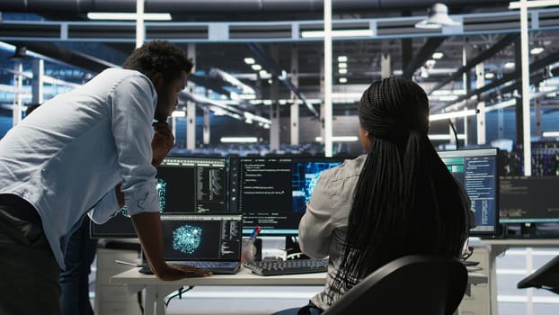 Data center manager supervising worker deploying AI solutions optimizing equipment. Server farm supervisor overseeing programmer using artificial intelligence to minimize systems downtime, camera A