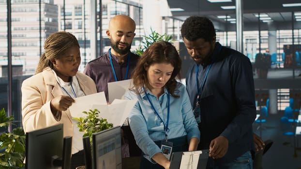 Portrait of smiling workers in office working together on finishing project before deadline, doing brainstorming. Team of upbeat office clerks cooperating on tasks, crosschecking documents, camera A