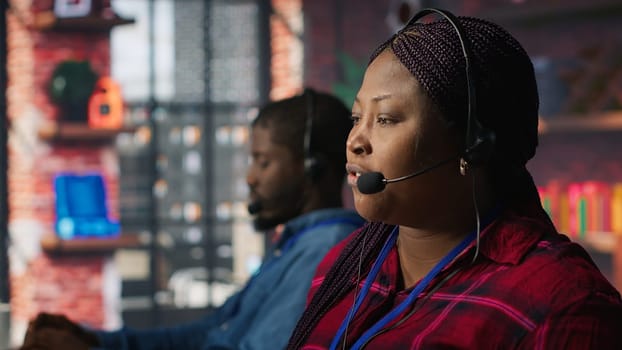 Call center agent listening to customer needs, providing step by step guidance. Customer center worker manages incoming and outgoing calls, walking clients through technical solutions, camera A
