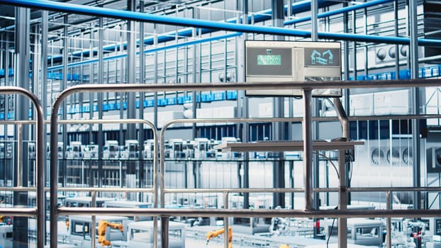 Monitor displaying industrial automation software overlooking industry 4.0 smart factory with robotic arms, modular production units, connected machines and control systems