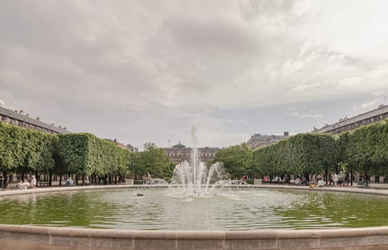 France, Paris - May 03, 2025 - View of Fountain in the Jardin du Palais Royal with the Palais Royal building and sky in the backhground. known as "Fontaines de Pol Bury" use it as your Wallpaper, Poster and Space for text, Selective focus.
