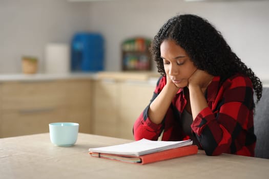 Black student learning reading notes in a kitchen at home