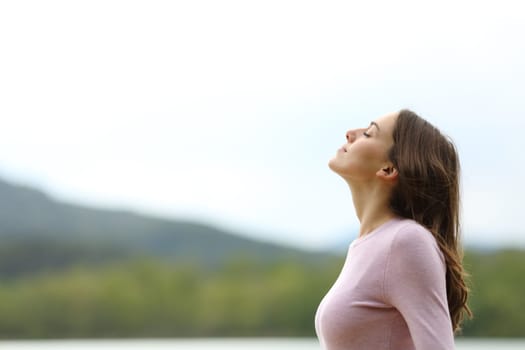 Side view portrait of a woman in nature breathing fresh air alone