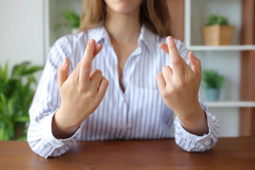 Front view close up portrait of a woman hands crossing fingers in a house interior