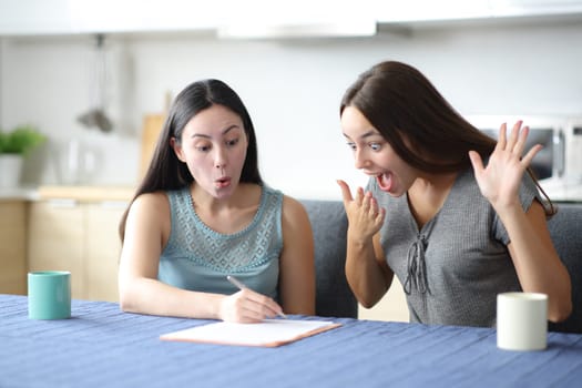 Amazed interracial women checking contract in the kitchan at home