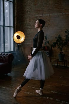 A graceful ballerina delicately poses in a stylish loft featuring minimalist decor and dramatic lighting effects