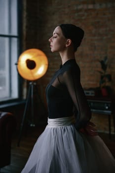 A graceful ballerina delicately poses in a stylish loft featuring minimalist decor and dramatic lighting effects