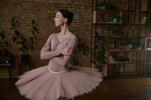 Ballerina is showcasing her exceptional grace while wearing a soft peach tutu in a modern studio space