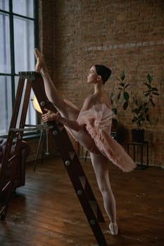A ballet dancer showcases elegance and flexibility while stretching on a ladder in a stylish studio.