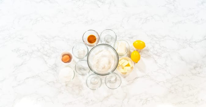 The image shows the ingredients for Lemon Spritz Cookies, including flour, sugar, butter, eggs, and fresh lemons, ready for baking.