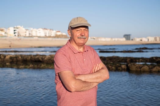 An elderly man with a mustache walking on the beach
