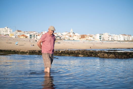 An elderly man with a mustache walking on the beach