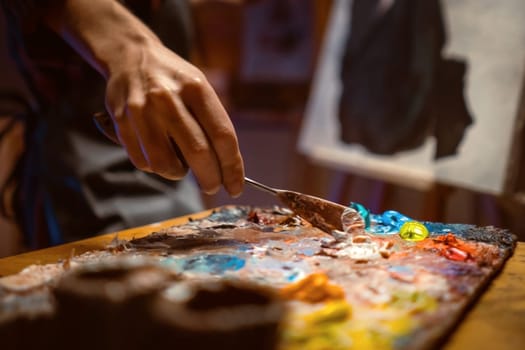 .Female artist Working on oil painting. In her hands are brushes and a palette. She paints a picture in the mysterious atmosphere of her studio.