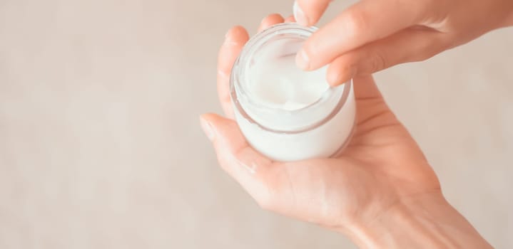 Young female hands hold a jar of moisturizing cream to maintain health, softness of the skin, the woman takes care of her health and beauty.