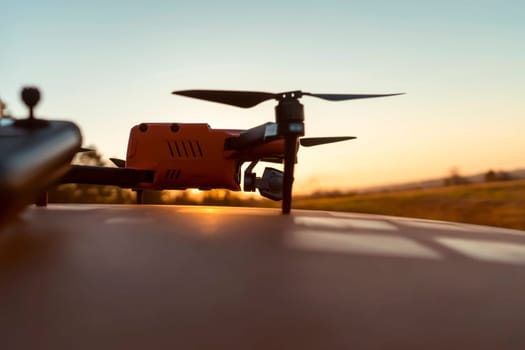 A drone and remote control against the sunset outdoors, in the rays of the sun. UAV technologies for monitoring territories, secret missions from the air, agricultural purposes and security.