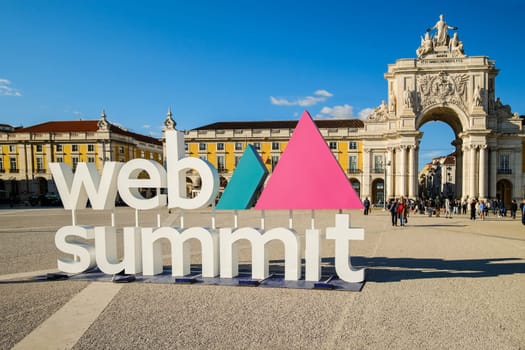 Nov 13, 2024 - Lisbon, Portugal: Web Summit sign displayed at Commerce square on sunny day under clear blue sky, people walking around. Major annual technology conference, internet technology, emerging technology, marketing, AI solution
