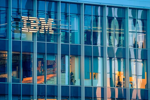 Jan 16, 2025 - Lisbon, Portugal: Day view of IBM office building with glowing logo and sleek glass exterior. Illuminated interior spaces and reflections, innovative spirit and global presence of renowned technology corporation, corporate life