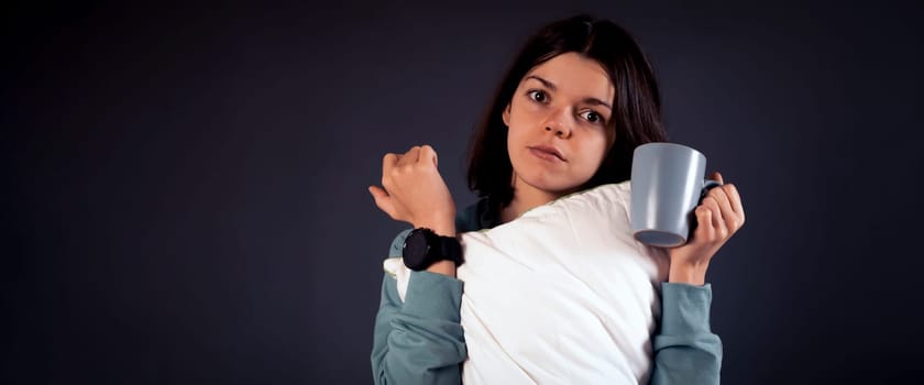 A funny girl anxiously points to the clock on her hand, young woman is in a hurry and late, reminds of the deadline during student practice, work and sets the alarm clock.