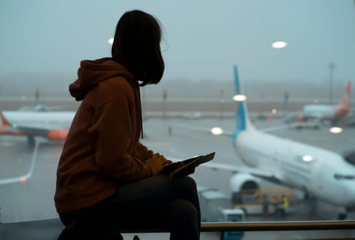 A young girl at the airport is boarding a plane in the evening, waiting for her flight. A woman goes on a journey.