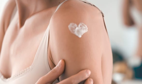 A young girl applies a moisturizer to her skin, a woman gently cares for her body, depicts a heart with a cream, taking care of herself, beauty and health.