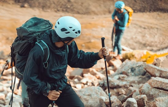 Two climbers hike to the top of the mountain with climbing, tourist equipment, men in helmets, with a rope and backpacks travel through the mountains, rocky terrain.