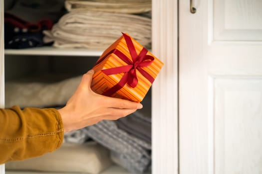 A funny young girl is in a hurry to hide a gift for a loved one, husband, children, friends and parents, a woman wants to make a surprise and hides the gift in the closet during holidays.