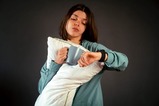 A funny girl anxiously points to the clock on her hand, young woman is in a hurry and late, reminds of the deadline during student practice, work and sets the alarm clock.