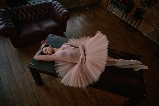 A ballet dancer lies elegantly on a table, showcasing her delicate tutu in a captivating artistic setting