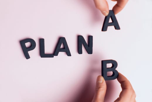 Top view of the scattered letters and the inscription, folded into the words "plan a", the hands of people replace the letter a with b. Creative concept about plan b, strategies and opportunities.