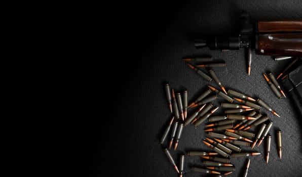 AKS-74U assault rifle and cartridges 5.45 for it lie on a dark background, a firearm with a magazine, a concept on a military army theme and weapons.