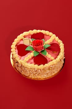 Round cake with pink icing, decorated with hearts, rose and green leaves, for braun family, on red background