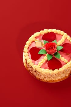 Round cake decorated with hearts, rose and whipped cream on red background